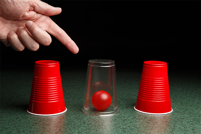 Shell game: looking for a ball under cups.