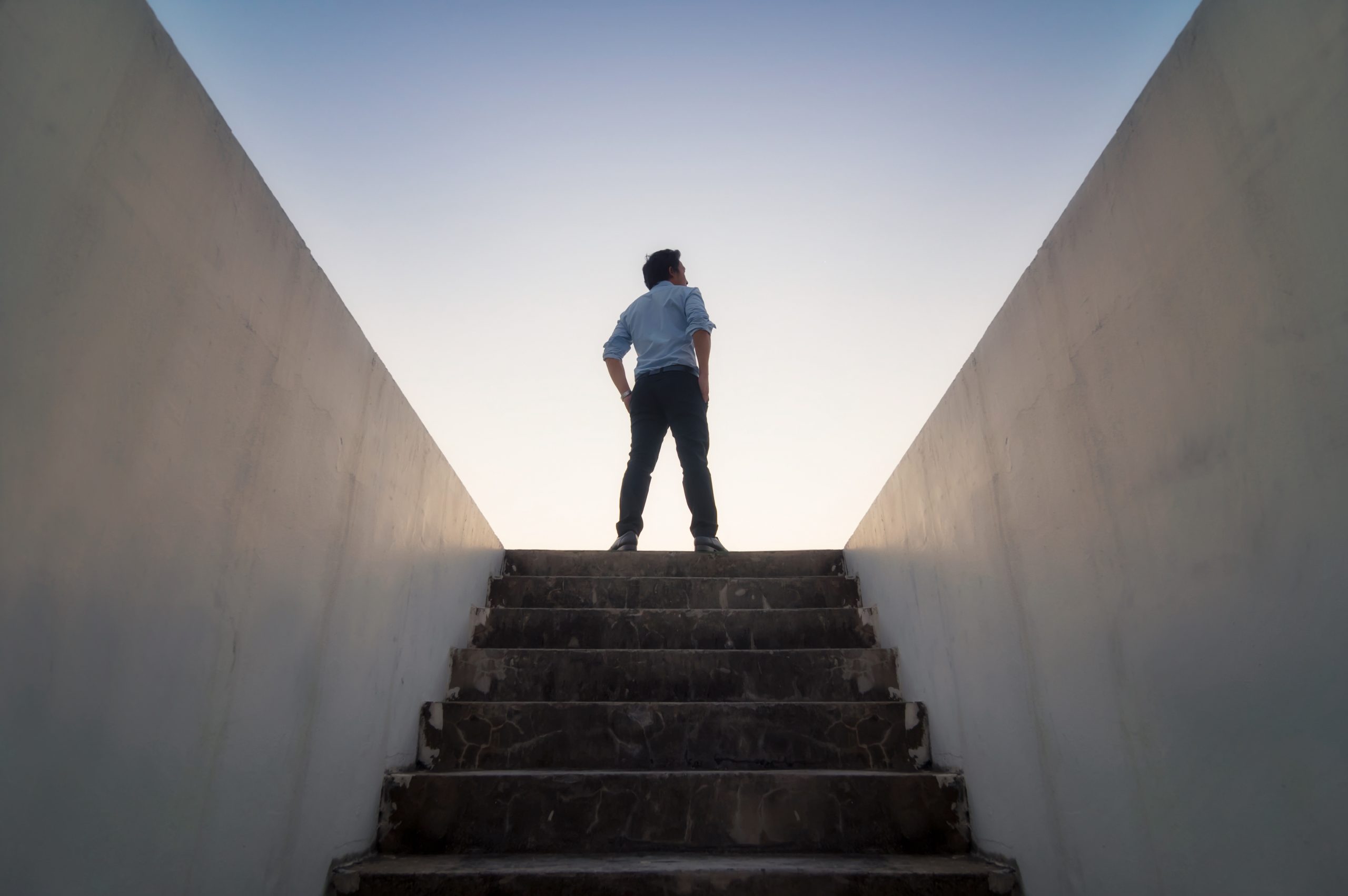 Businessman climbed to top of the stairs going to the city at dawn.