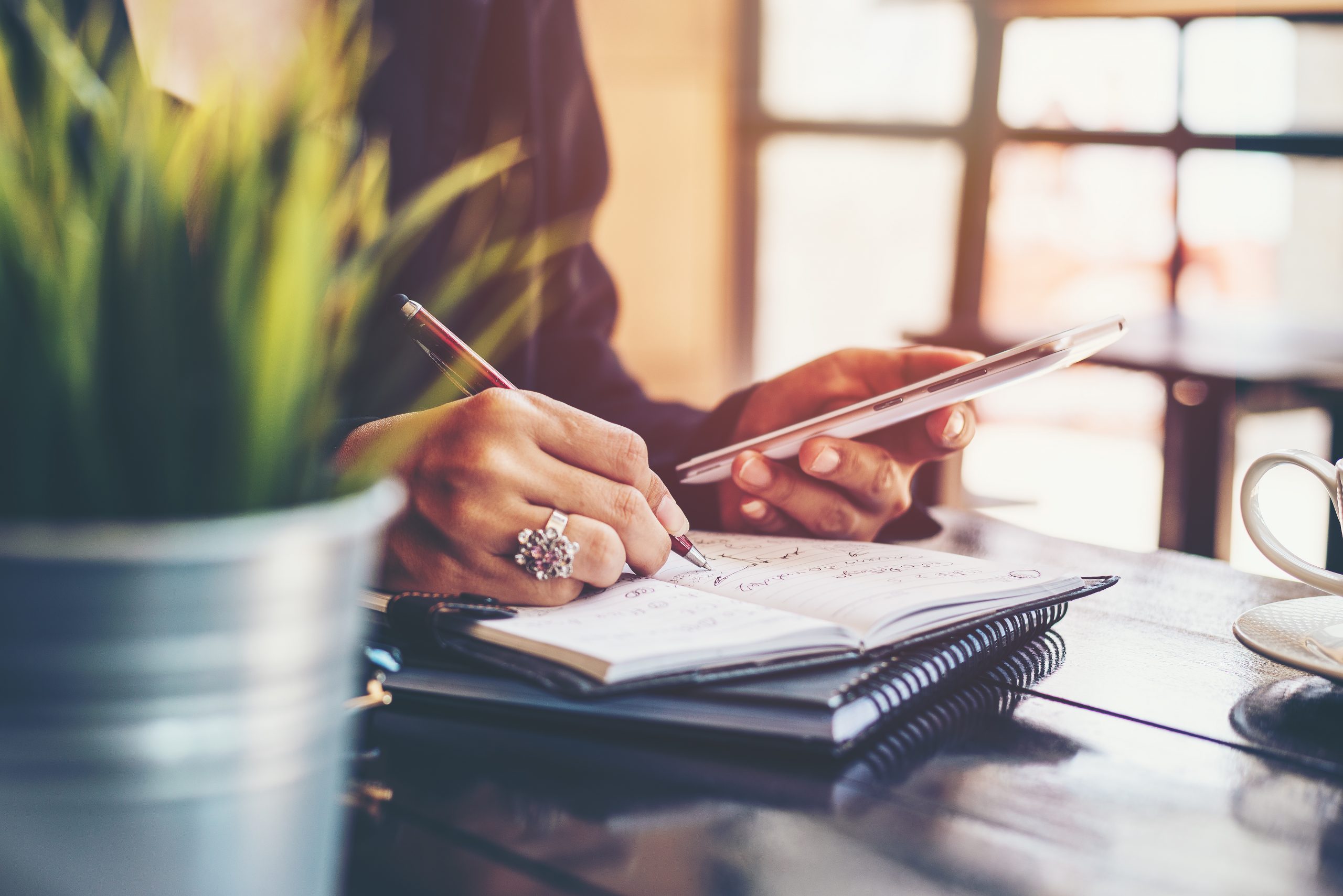 A close-up of a fundraiser planning her donor touch points while writing in a notebook.