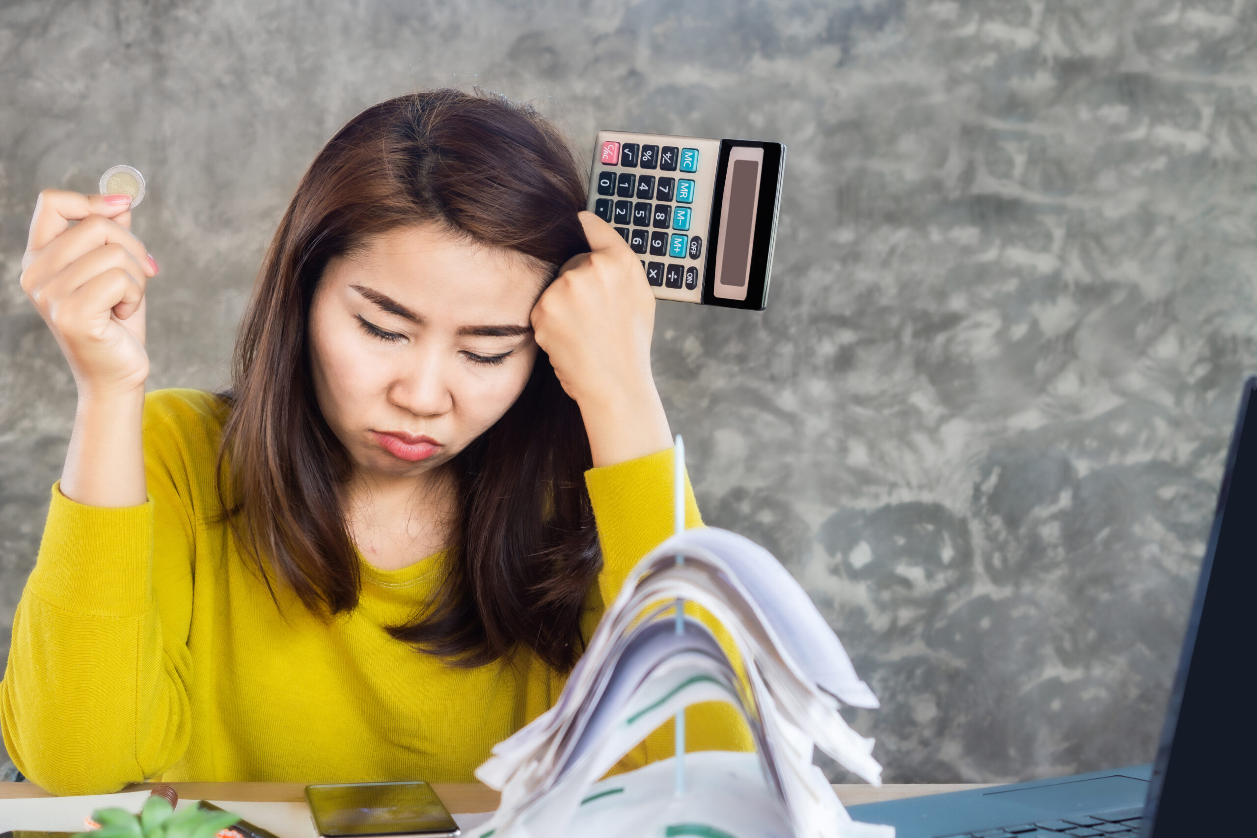 A woman is stressed out, holding a coin and a calculator. [Get Rid of Your Giving Club]