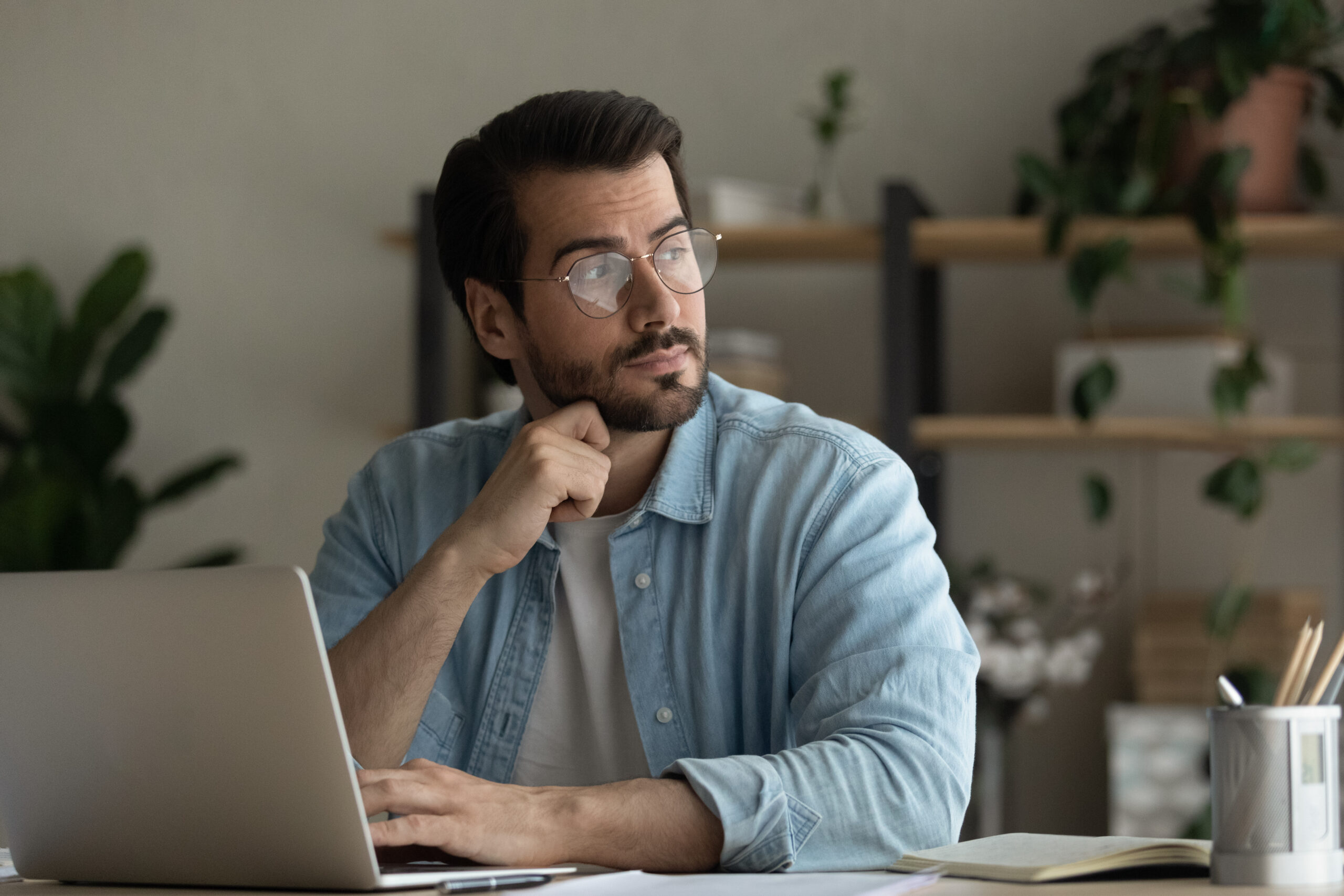 Man in glasses sitting at his computer and looking off in contemplation. [Why Am I Failing at My Job?]