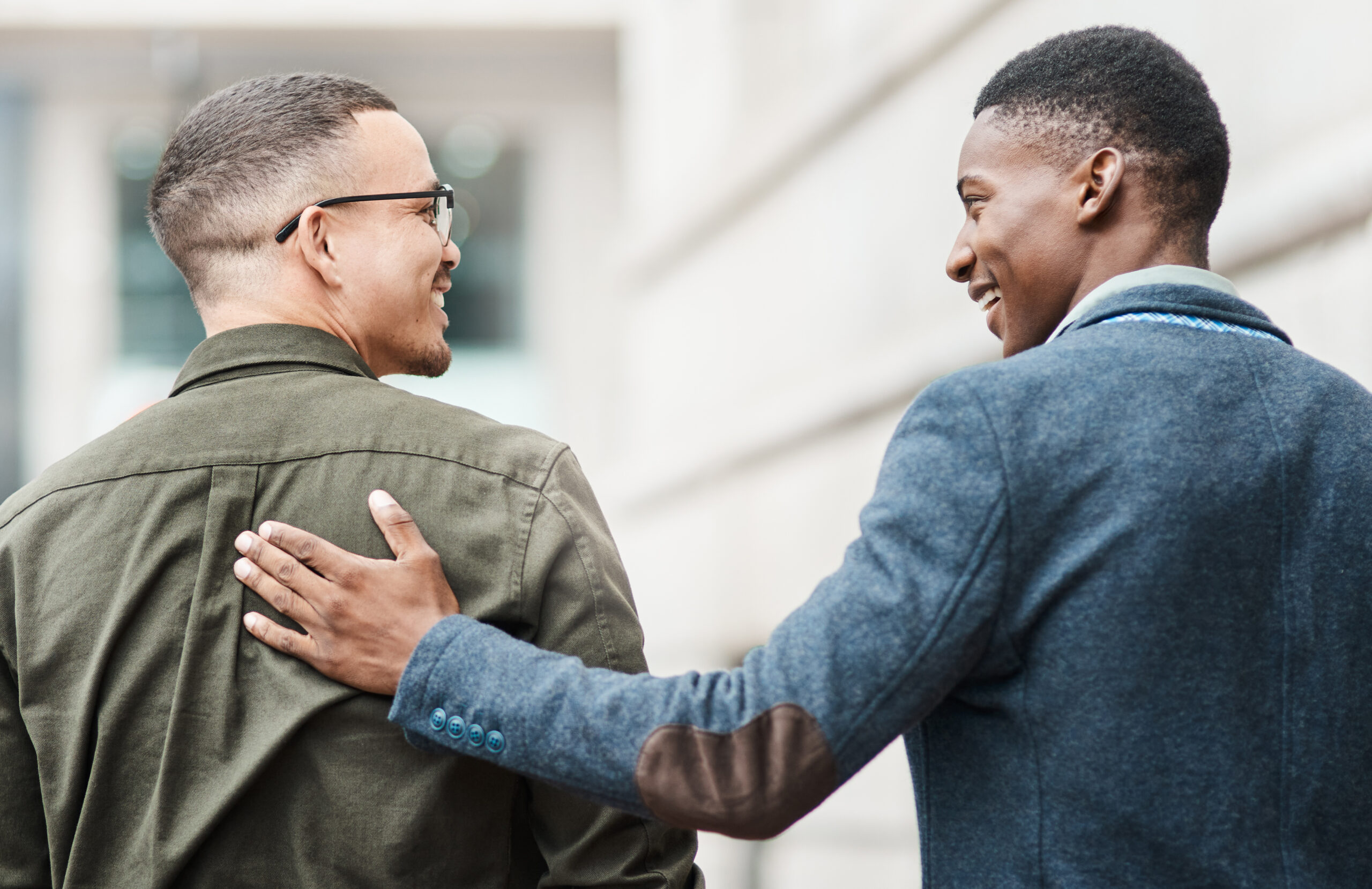 Two men walking through the city together while smiling. [The Danger of Becoming Your Donor's Friend]