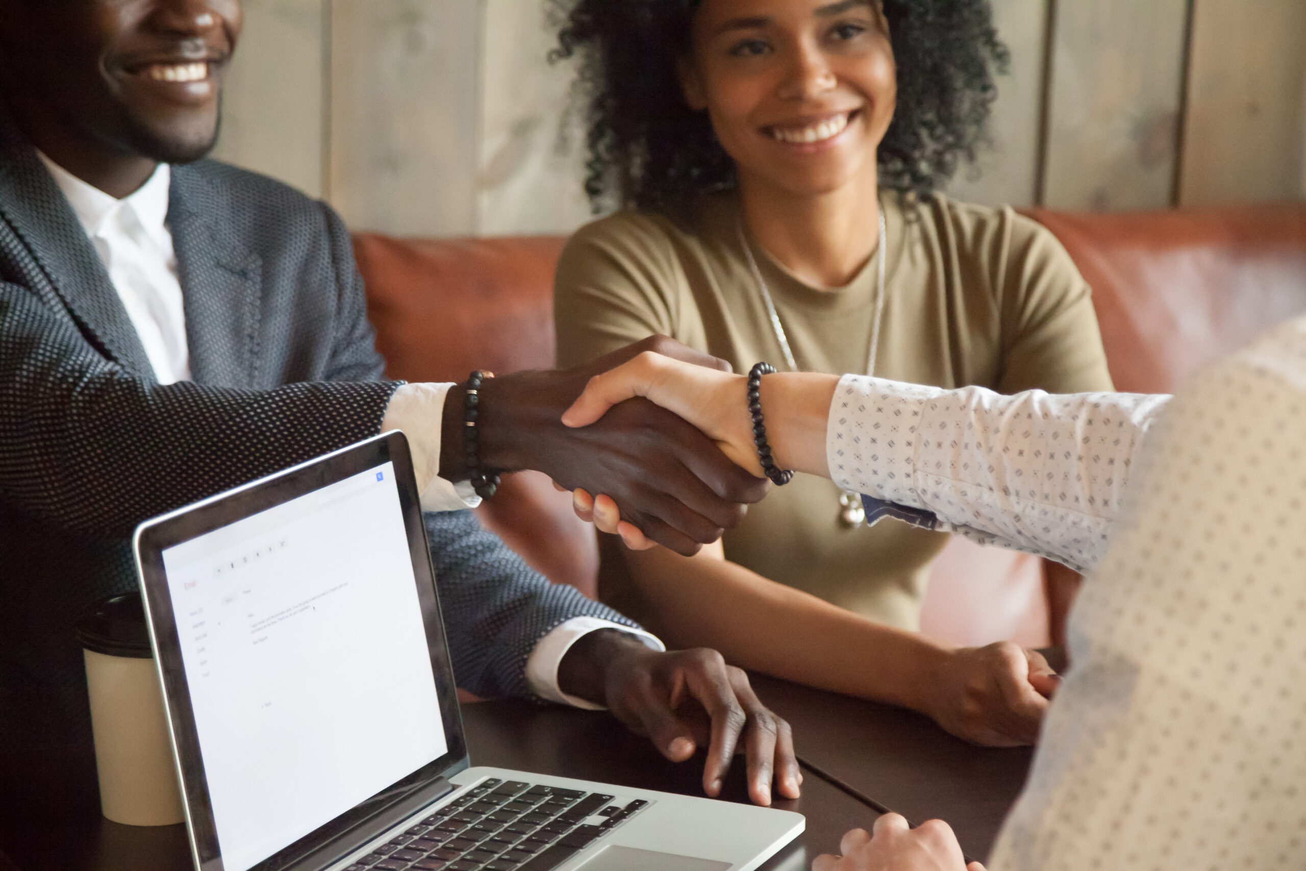 Three people are sitting down together and two of them are shaking hands [Make it Meaningful: 3 Questions to Help Move Your Donor Relationship Forward]