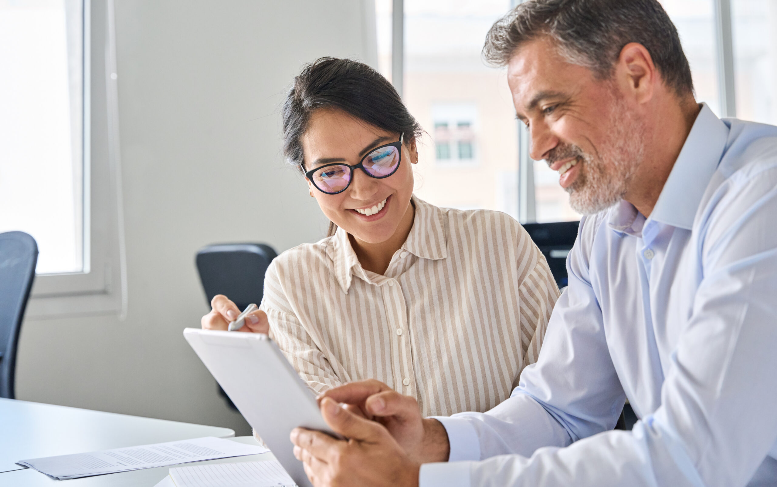 A fundraiser sits next to a donor in an office setting while reading a document together [A Donor Performance Report Delivers a Practical & Relational Gift]